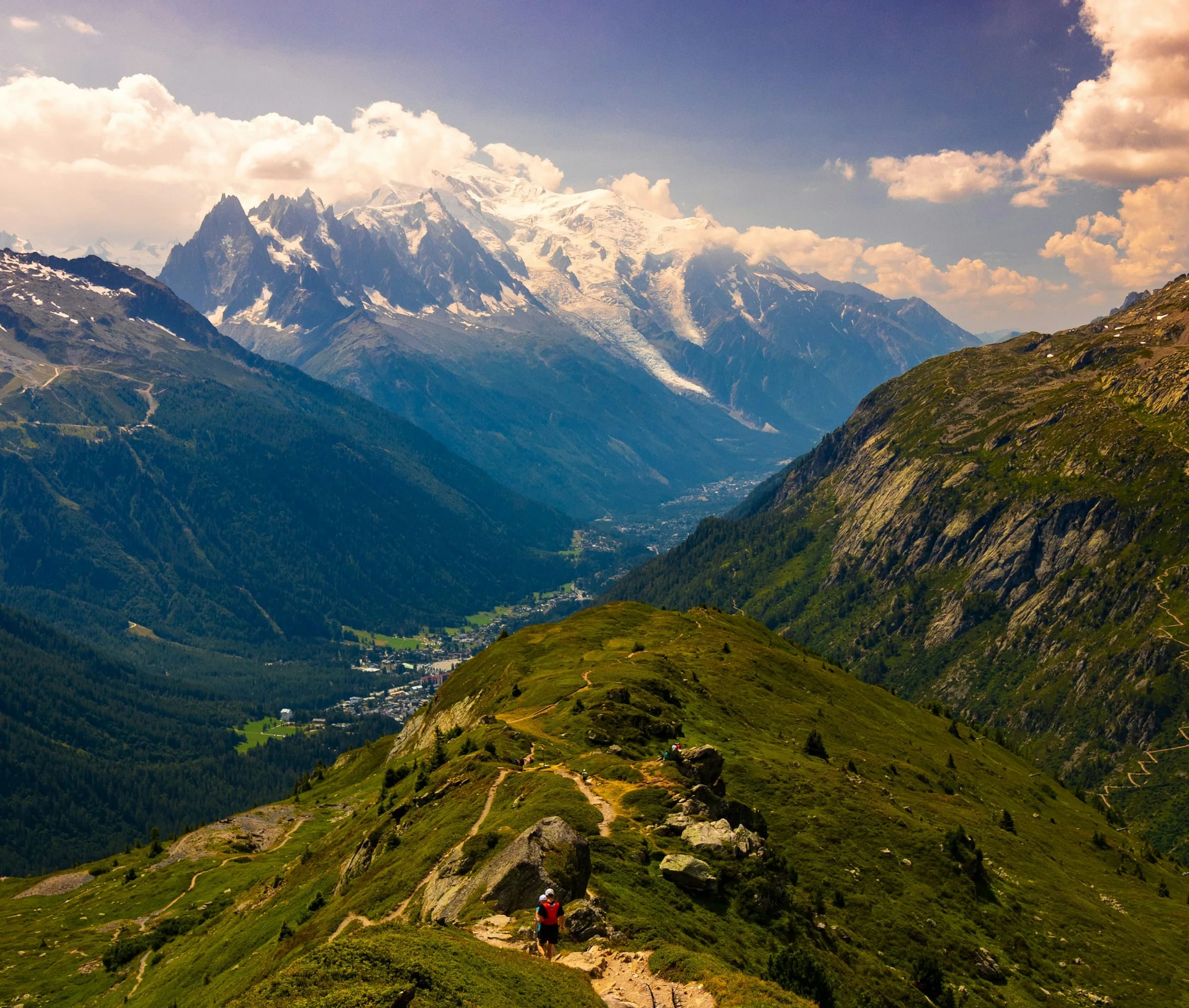 Hikers on a ridge trail high above the Chamonix valley, with the Mont Blanc massif beyond