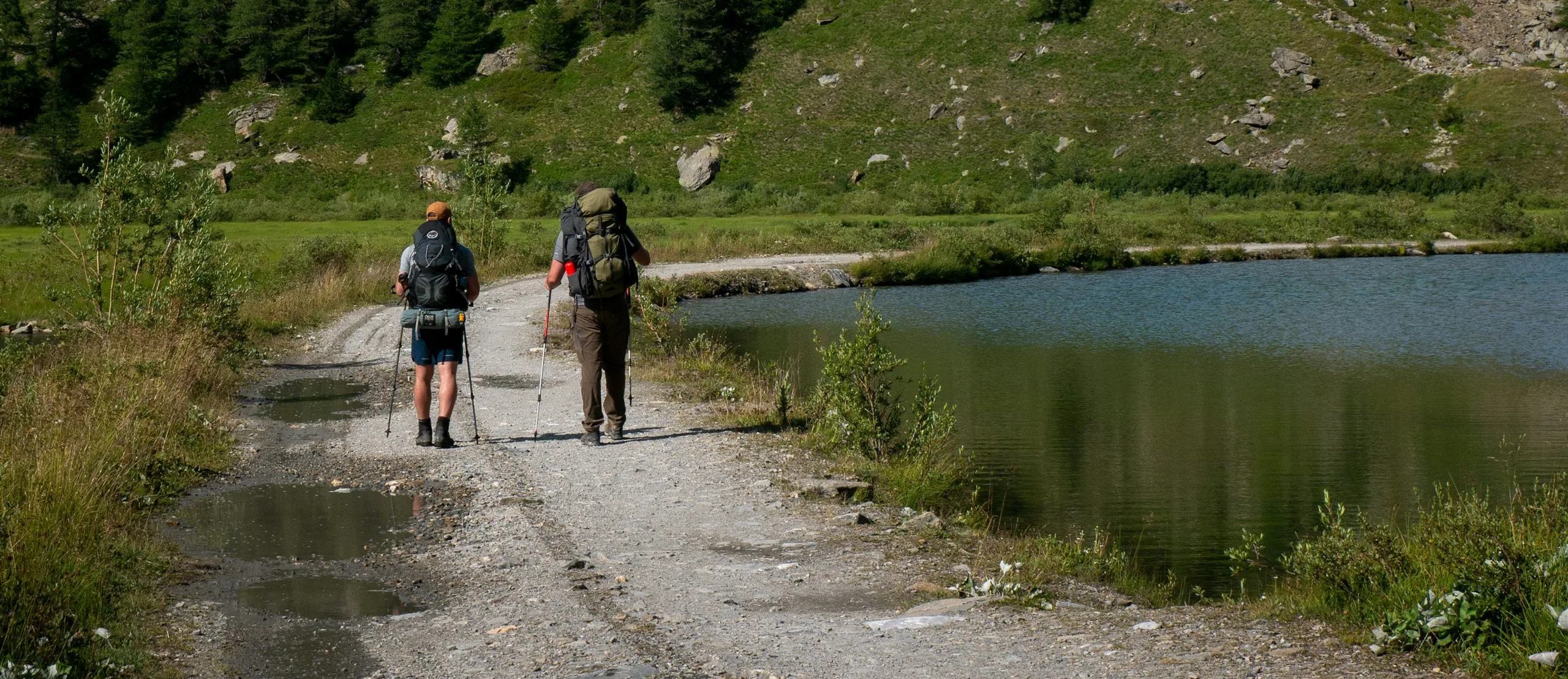 A guide and guest on a valley track beneath the Mont Blanc massif